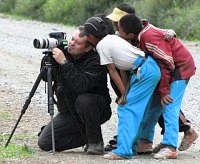 picture shows photographer and tourguide peter pap on a trip in tibet 2007 taking photos while tibetan children are watching